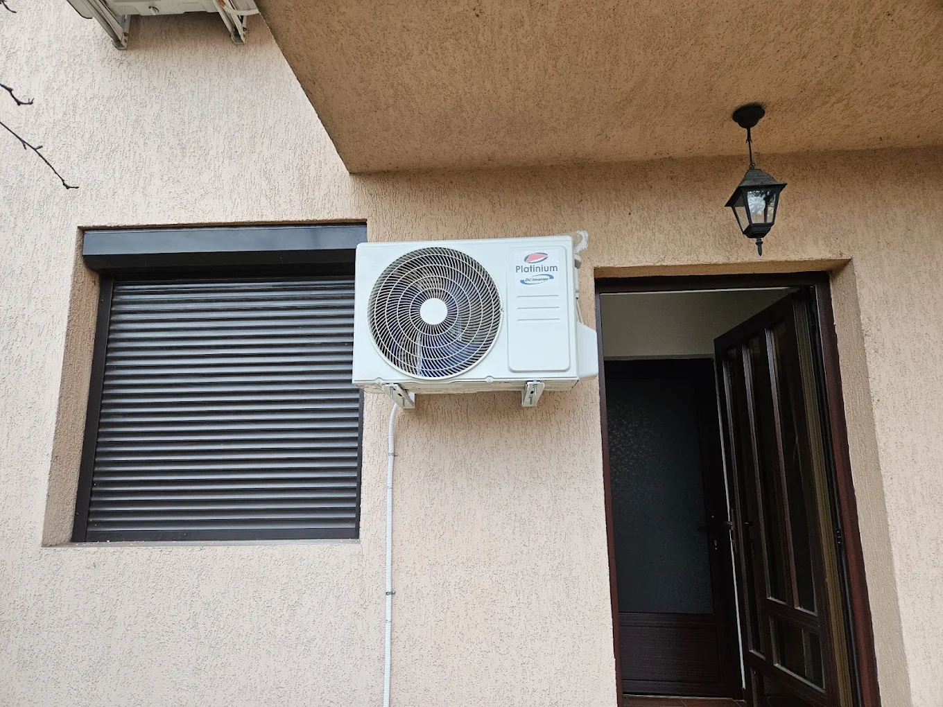 Unitate exterioară de aer condiționat montată pe fațada unei locuințe