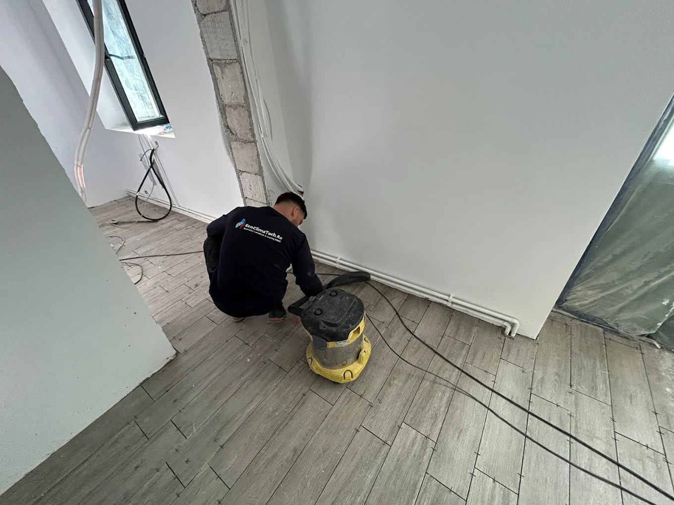 Tehnician EcoClimaTech curățând zona de lucru cu un aspirator
