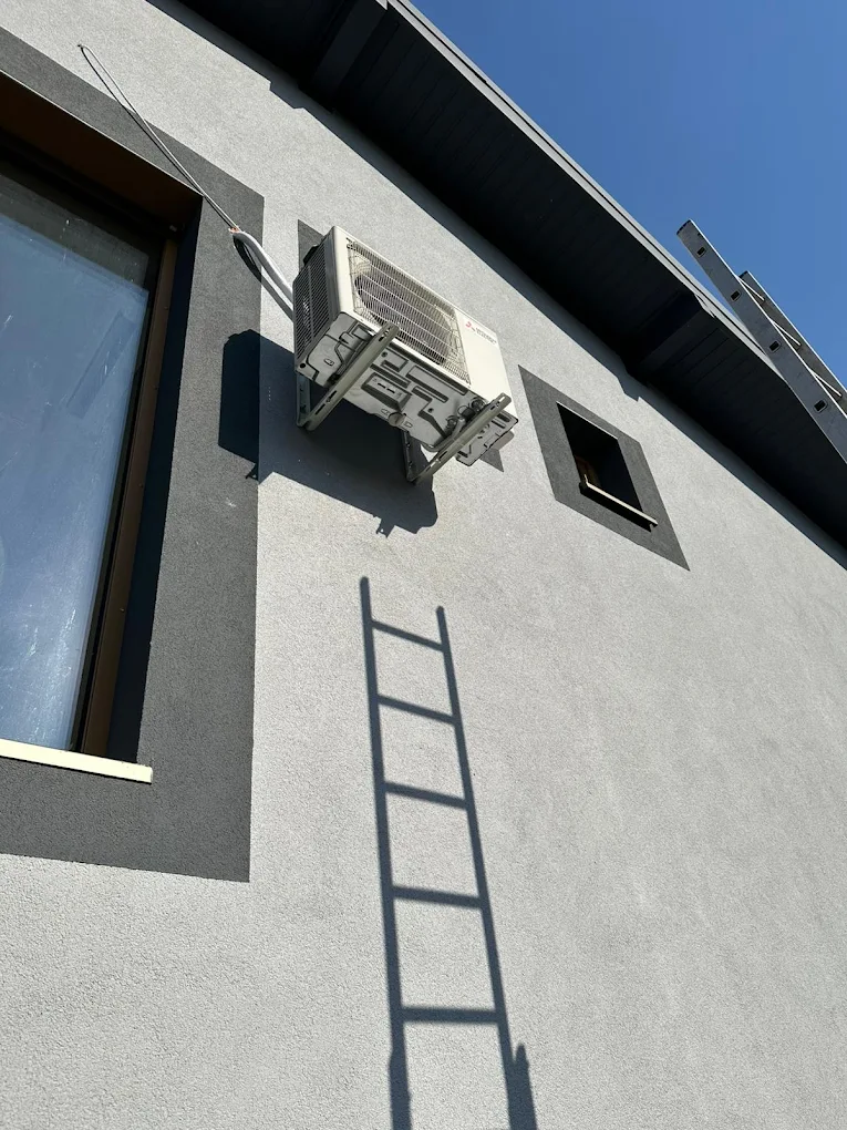 Unitate exterioară instalată pe console pe o fațadă gri